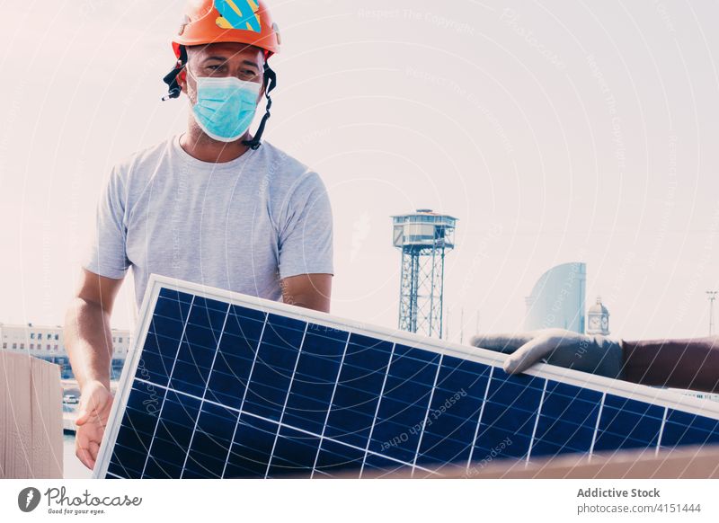 Männlicher Arbeiter mit Maske und Sonnenkollektor solar Panel installieren Batterie Mann Ingenieur alternativ nachhaltig Kraft männlich Entwicklung Energie