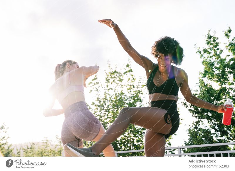Fröhliche, sportliche Freundinnen haben Spaß im Park Frauen Fitness Spaß haben heiter Training ruhen Energie Erholung Glück springen Tanzen aktiv Freude