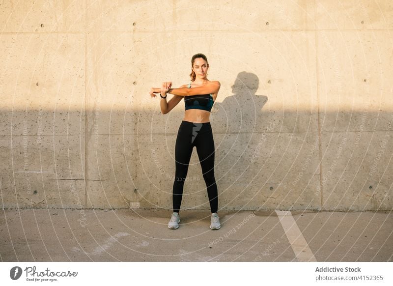 Schlanke sportliche Frau streckt ihren Körper an einer Betonwand Sportlerin Dehnung Übung passen schlank Aufwärmen Training Straße aktiv jung Wand Energie
