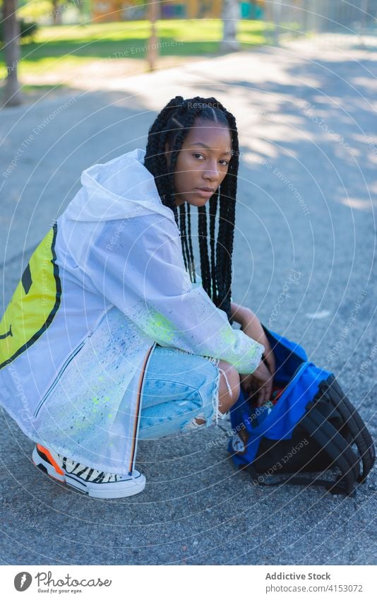 Junge schwarze Frau mit Tasche im Park sitzend Mode Stil Jeansstoff trendy jung Hipster Geflecht urban Streetstyle ethnisch Afroamerikaner tausendjährig