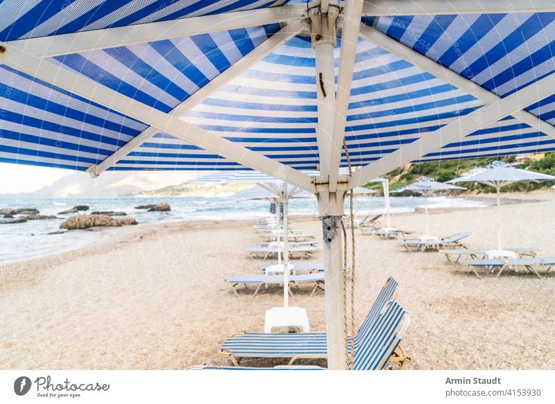 Liegestühle und Sonnenschirme an einem leeren Strand Hintergrund Bucht blau Stuhl Wolkenlandschaft Küste Küstenlinie Schiffsdeck Liegestuhl Feiertag Reise