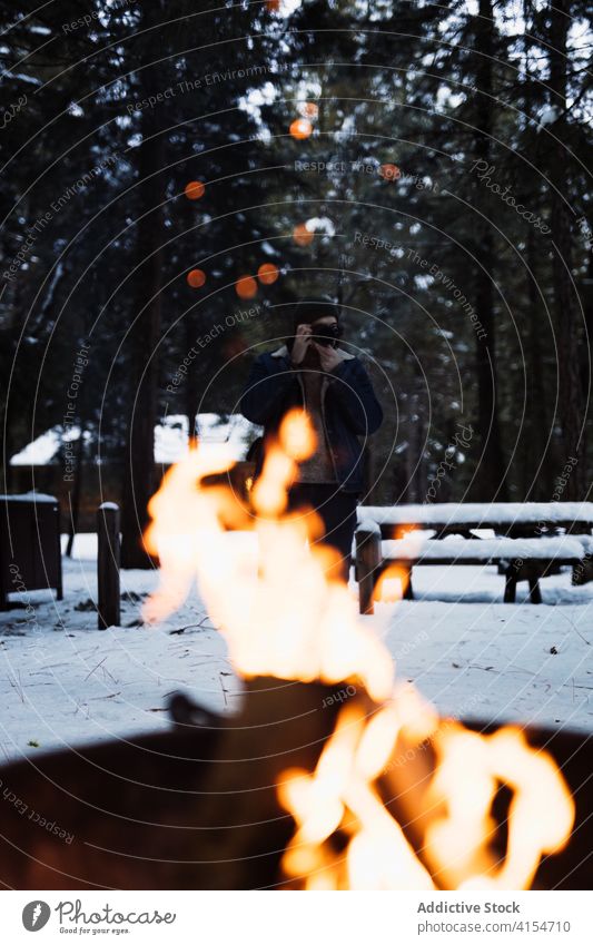 Reisende, die ein Lagerfeuer im Winterwald fotografieren Freudenfeuer Wald Reisender Fotograf Flamme Schnee Feuer Feuerstelle kalt Saison Abenteuer Natur Wälder