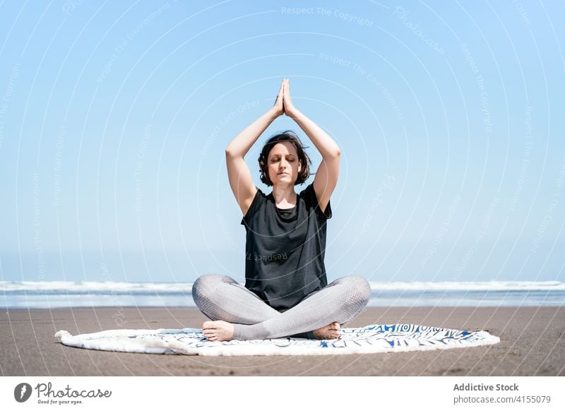 Schlanke Frau beim Meditieren am Strand Yoga MEER üben Asana Pose verdrehen Augen geschlossen sitzen Gleichgewicht Windstille Meeresufer Harmonie Wellness