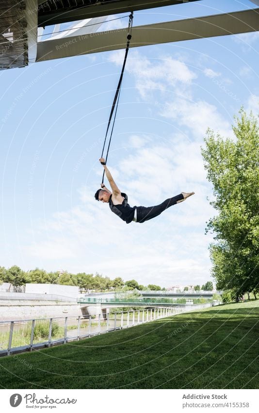 Flexibler Mann trainiert an Traggurten Antenne Gurt Turner Training gymnastisch hängen ausführen beweglich passen Park männlich Übung Energie Athlet Sport