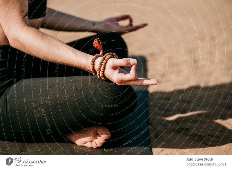 Anonyme entspannte Frau in Lotus-Pose am Strand Yoga padmasana meditieren Mudra Unterlage Zen friedlich Gesundheit sich[Akk] entspannen passen Natur Energie