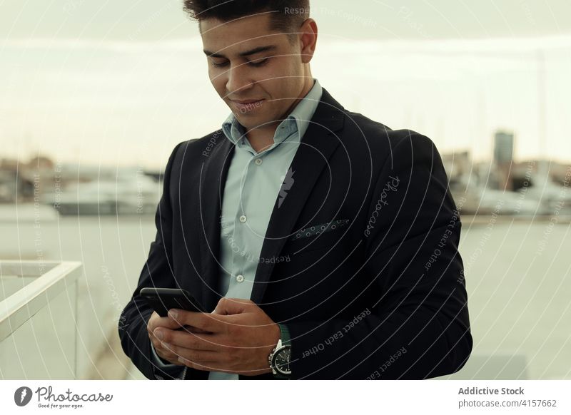 Fröhlicher Geschäftsmann am Mobiltelefon in der Stadt Unternehmer Großstadt Smartphone Text Inhalt formal Anzug benutzend männlich Manager Gerät Exekutive Job