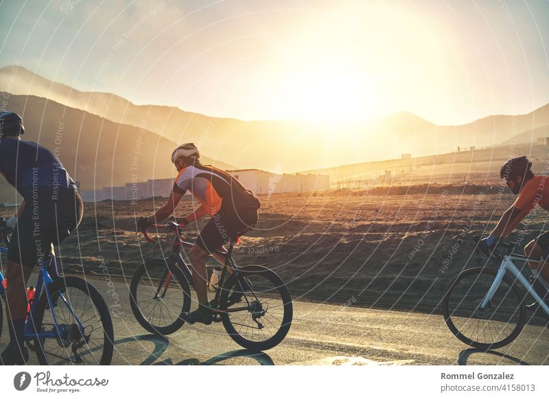 Gruppe von Radfahrern Freunde Reiten Rennen Fahrrad auf Sonnenuntergang Autobahn, Sonnenuntergang Fahrrad Wettbewerb. Menschengruppe Fahrradfahren professionell