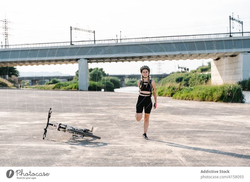 Radfahrerin streckt die Beine auf der Straße Frau Fahrrad Dehnung heiter Aktivität Glück sportlich Übung jung Schutzhelm vorbereiten Aufwärmen Lifestyle Sport