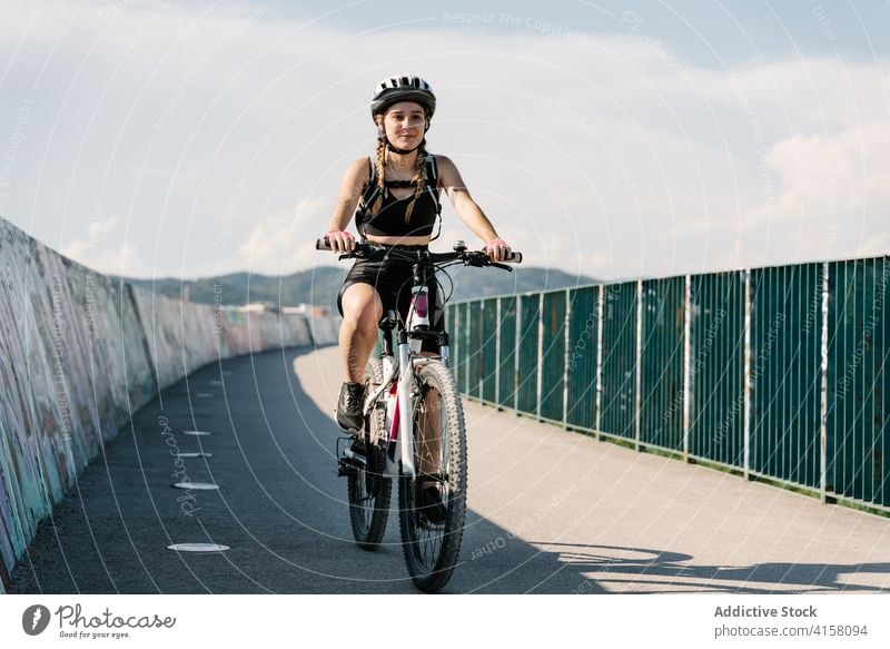 Aktive Frau fährt Fahrrad auf einer asphaltierten Straße Mitfahrgelegenheit Radfahrer Aktivität sportlich Weg Sport Übung jung Schutzhelm Lifestyle genießen