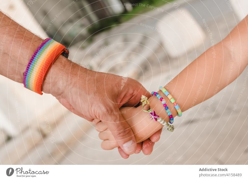 Crop homosexuellen Vater und Kind halten die Hände schwul Händchenhalten Homosexualität Mann Vaterschaft Regenbogen Armband Zusammensein wenig Großstadt