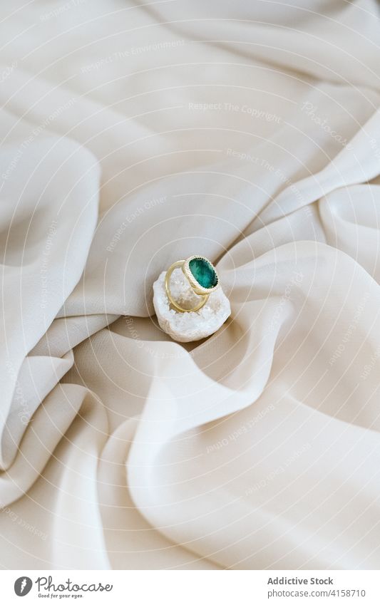 Eleganter Ring auf weißem Quarz elegant Kostbarkeit Juwel Schmuck Reichtum Stein natürlich Accessoire Spielfigur weich Bett Seide Gewebe Textil Stoff filigran