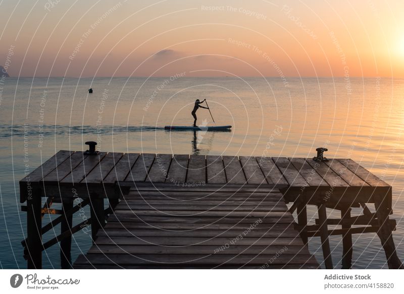 Frau rudert auf einem Paddelbrett im Meer Surfer Brandung Silhouette Sonnenuntergang Reihe MEER üben Training Zusatzplatine Surfbrett Sommer Holzplatte