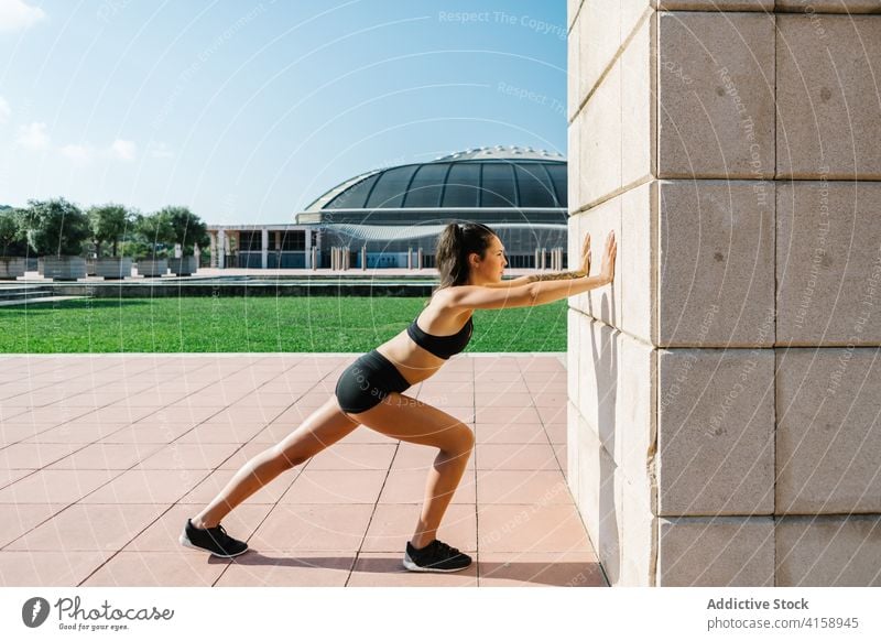 Sportliche Frau macht Dehnungsübungen in der Nähe der Wand Training Übung Wade Straße urban Athlet passen Sportlerin Läufer Jogger Muskel jung schlank Fitness