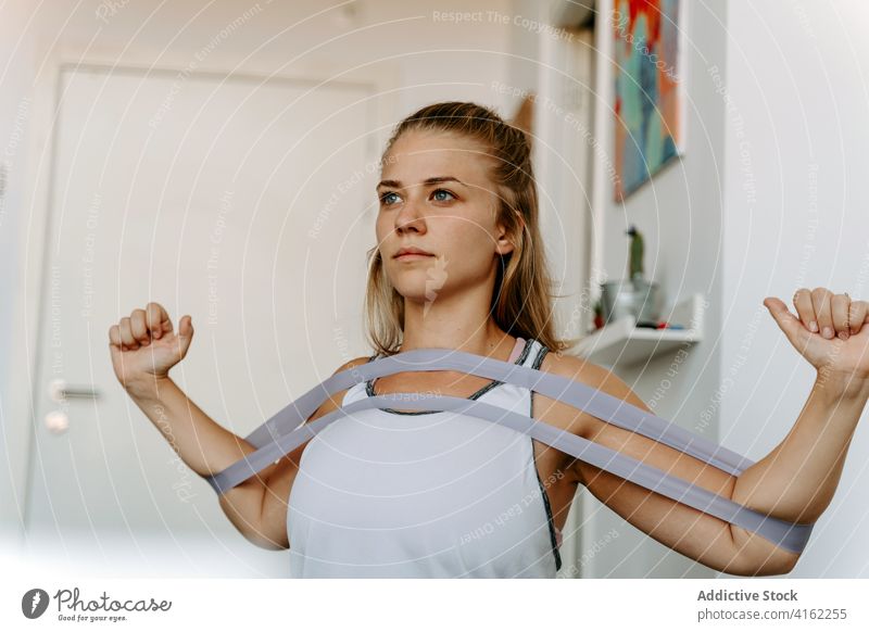 Sportlerin beim Training mit Gummiband zu Hause Übung Widerstandsband Vitalität Energie üben schlank Frau Aktivität physisch Sportbekleidung Wellness Fitness