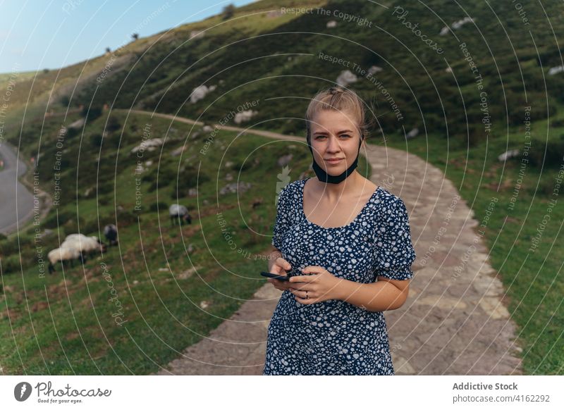 Frau mit gesenkter Gesichtsmaske in üppiger Hügellandschaft positiv Gelassenheit Hügelseite Landschaft Natur charmant Inhalt erstaunlich Berge u. Gebirge Umwelt