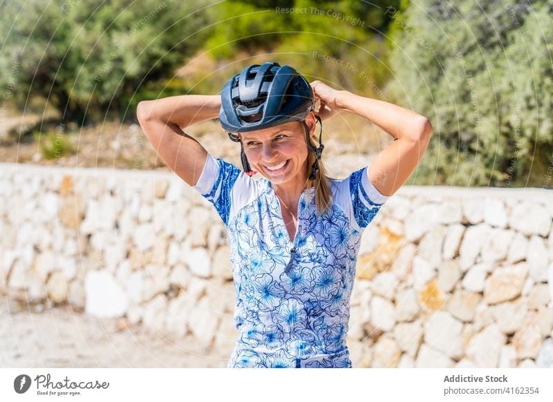 Fröhliche Frau setzt Fahrradhelm auf Radfahrer Schutzhelm aktiv Glück vorbereiten sportlich behüten heiter Mitfahrgelegenheit jung Lachen Sicherheit Lifestyle