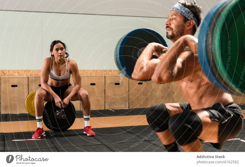 Sportler im Fitnessstudio beim Gewichtheben Kniebeuge Curl-Hantel Training muskulös Stoßen und Stoßen Ausdauer anstrengen Stärke intensiv schwer Athlet stark