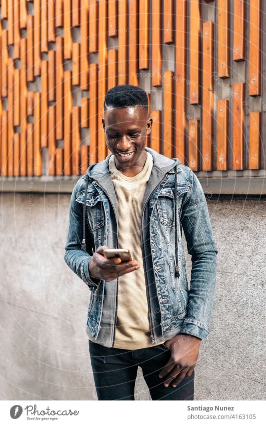 Porträt eines jungen afroamerikanischen Mannes Afroamerikaner Afrikanisch per Telefon Straße Tippen Handy Vorderansicht schauendes Telefon schwarz ethnisch