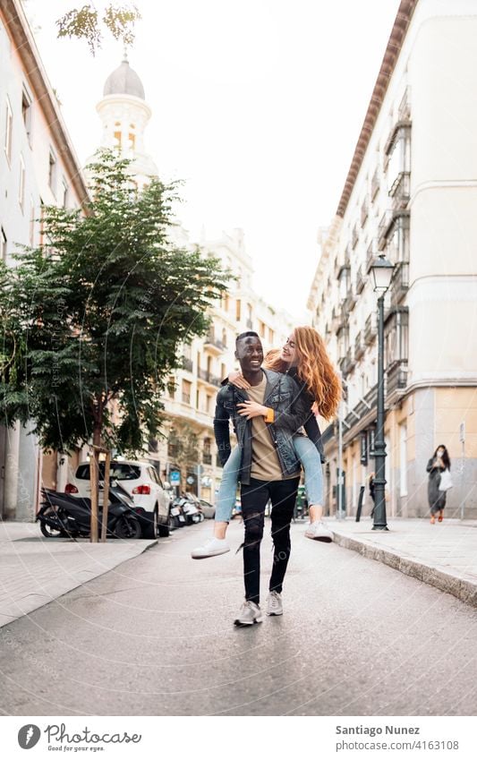 Schönes multiethnisches junges Paar laufen Spielen Spaß haben Straße Vorderansicht Porträt Partnerschaft multirassisch Schwarzer Mann Kaukasier multikulturell