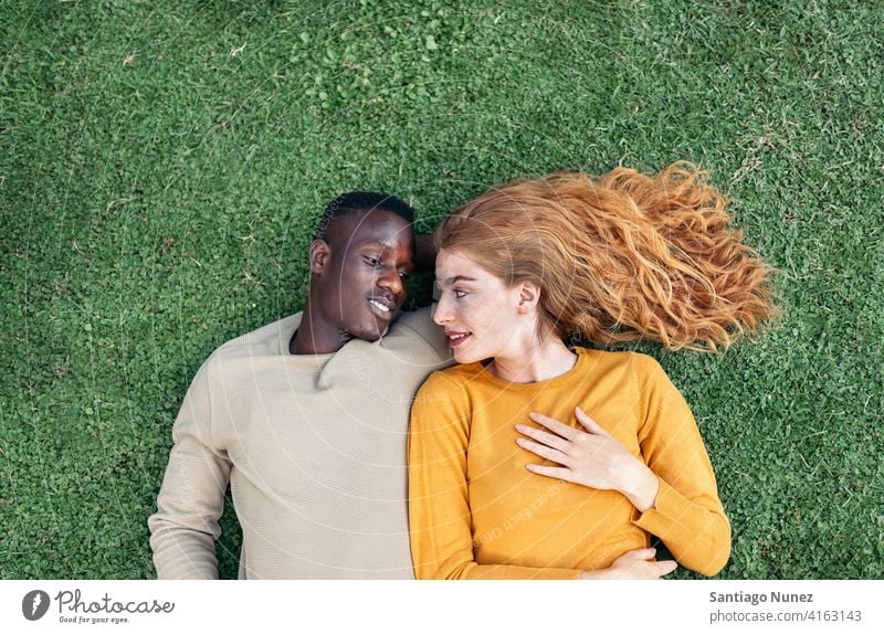 Multiethnische Paar Kuscheln im Gras Lügen die sich gegenseitig ansehen Draufsicht Porträt Partnerschaft multirassisch Schwarzer Mann Kaukasier multikulturell