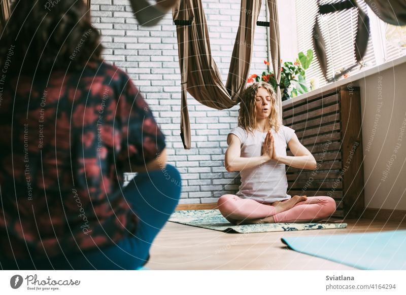 Zwei Frauen sitzen in einer Yogastunde auf einer Matte und meditieren nach einem Workout. Ruhe, Entspannung, Meditation Unterlage Pose Fitnessstudio sportlich