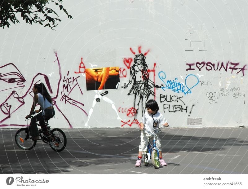 Phantasien in der Stadt Kind Mädchen Fahrrad Platz Wand Frau Mensch Tretroller Graffiti Fahrradfahren Spielen spielend Außenaufnahme