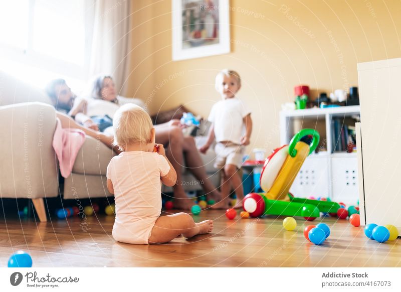 Säugling, der mit Eltern und Geschwisterkind in einem hellen Raum ruht Familie spielen Wohnzimmer Kindheit Baby Kinder Wochenende unschuldig Kleinkind Junge