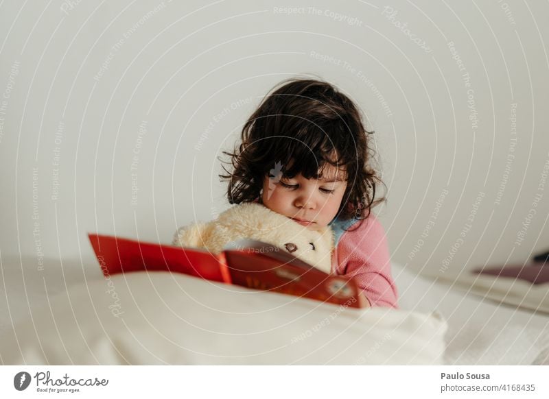 Kind liest Buch mit Teddybär Mädchen 1-3 Jahre Kaukasier lesen zu Hause Bett Lifestyle Farbfoto Mensch niedlich Spielzeug heimwärts authentisch Kindheit Pyjama