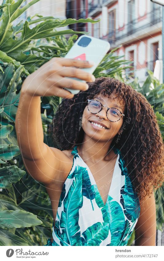 afrikanisches Mädchen macht ein Selfie mit ihrem Smartphone Frau Afrikanisch jung Handy Afro-Look Glück Telefon Fröhlichkeit schwarz Lifestyle Lächeln lockig