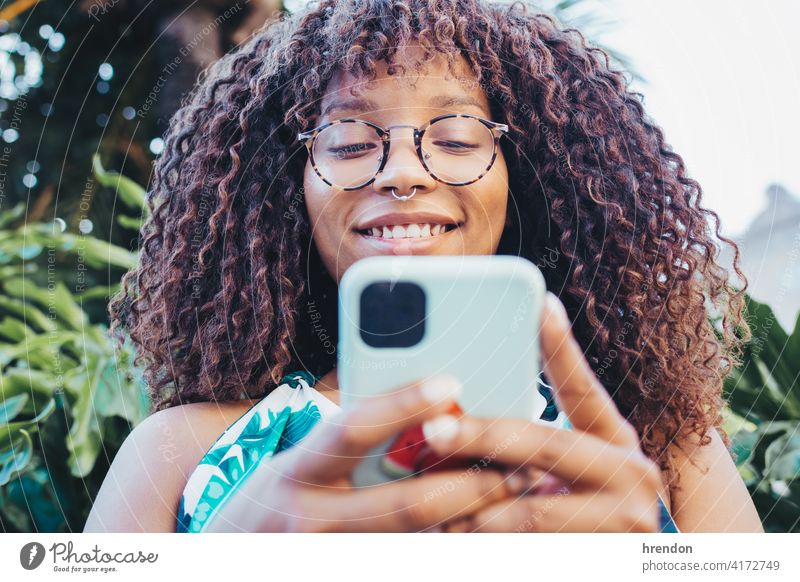 Nahaufnahme eines afrikanischen Mädchens mit ihrem Smartphone Frau Afrikanisch Telefon Behaarung Gesicht Mitteilung jung Technik & Technologie schwarz