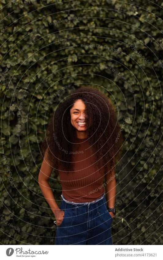 Glückliche ethnische Frau im grünen Garten charmant Lächeln natürlich Schönheit offen krause Haare Afro-Look Frisur Park schwarz Afroamerikaner jung heiter