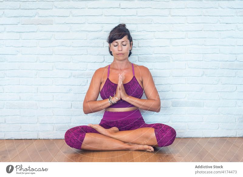 Frau meditiert in Lotus-Pose im Studio meditieren Yoga Lektion Atelier Hände gefaltet Augen geschlossen Achtsamkeit Zen Erwachsener Gleichgewicht Harmonie