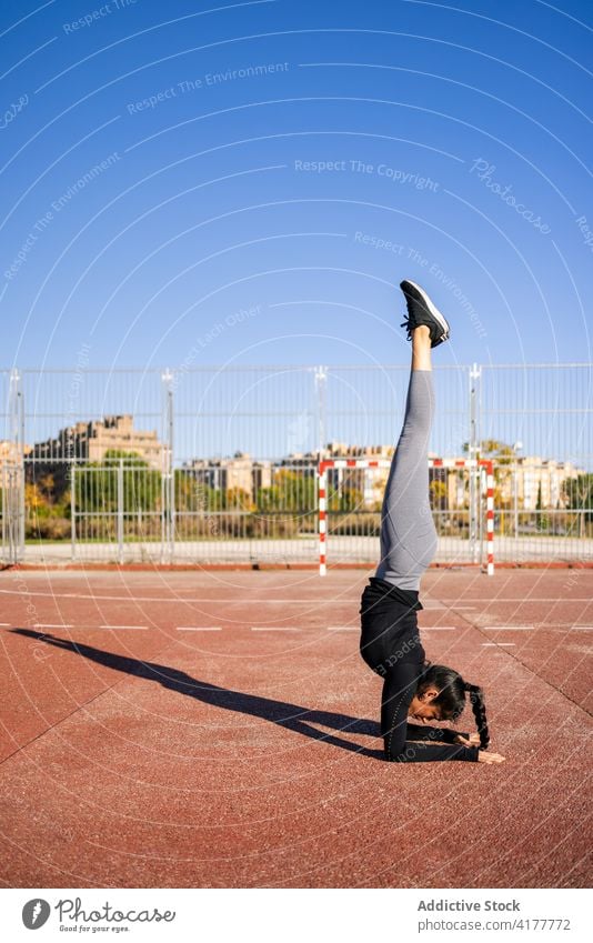 Sportliche Frau beim Handstand auf dem Sportplatz Übung Gleichgewicht Training calisthenics akrobatisch gymnastisch schlanke Athlet Sportbekleidung Wohlbefinden