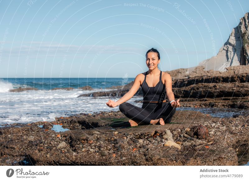 Entspannte Frau beim Yoga am Meer Strand meditieren Lotus-Pose Asana Mudra padmasana Meeresufer Beine gekreuzt Zen Natur Wohlbefinden Harmonie Küste Energie