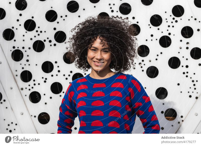 Fröhliche schwarze Frau in stilvollem Outfit in der Stadt Afro-Look Frisur Vorschein heiter urban lebhaft kreativ Großstadt ethnisch Afroamerikaner Pullover