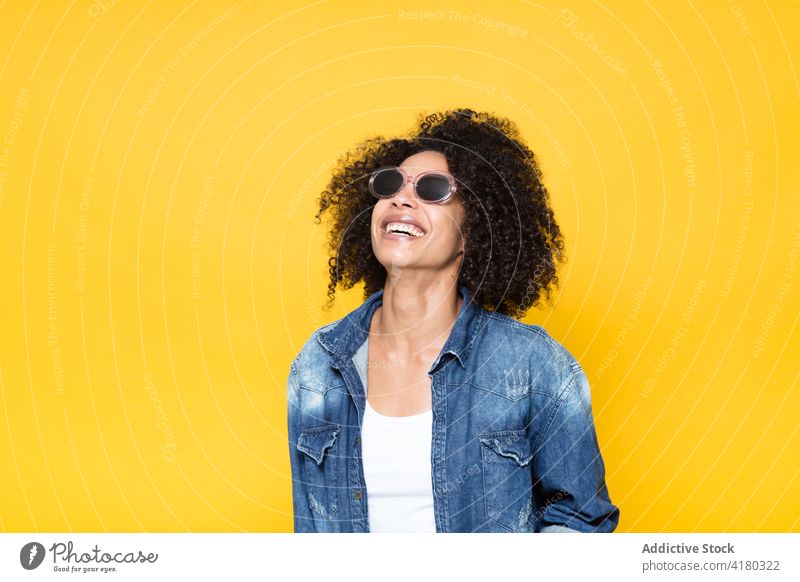 Fröhliche ethnische Frau in Jeanshemd schaut weg Sonnenbrille heiter Jeansstoff Lächeln lässig positiv trendy Glück Optimist krause Haare jung Afroamerikaner