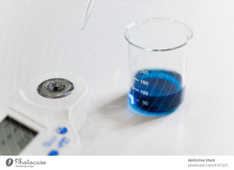 Chemische Flüssigkeit mit Glas während eines Experiments im Labor forschen Chemie Medizin Wissenschaft liquide messen Werkzeug Gerät Instrument Chemikalie blau