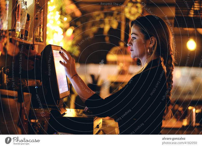 eine schöne junge Frau an der Rezeption in einem Restaurant Stehen Schreibtisch berührend Kasse bezahlen Manage Bar Lifestyle Touchscreen benutzend Rechnung