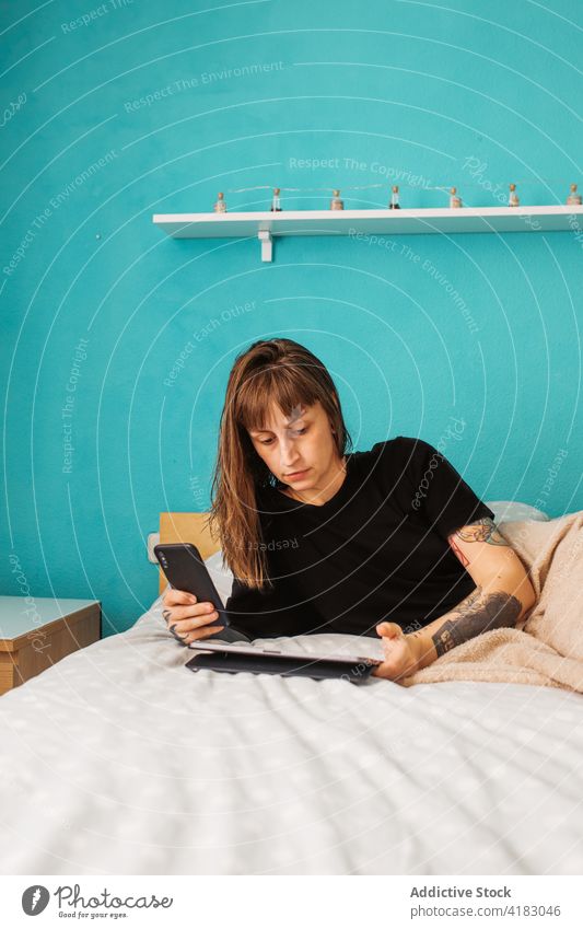 Konzentrierte Frau mit Tablet auf dem Bett benutzend Tablette Fokus Konzentration Smartphone Schlafzimmer Apparatur Browsen klug Surfen jung modern Internet