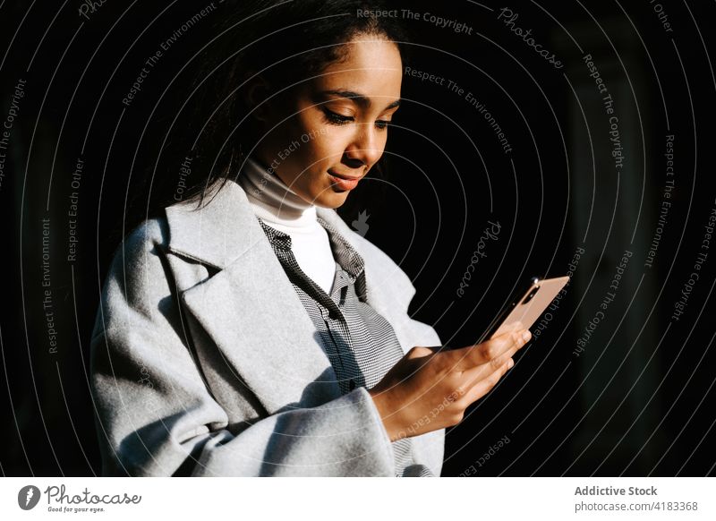 Junge Frau benutzt Smartphone auf der Straße benutzend urban Telefon Mobile Nachricht jung Stil ethnisch Lifestyle Apparatur Gerät Browsen online Internet