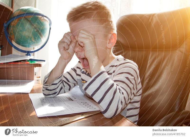 ein schulpflichtiger Junge, der bei den Hausaufgaben weint und schreit. das Konzept der "heavy pressure education Schule heimwärts Kind Schüler wütend Stress