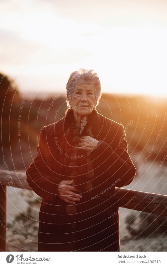 Ältere Dame bewundert den Sonnenuntergang über dem Meer von der Strandpromenade aus Frau bewundern Meereslandschaft Reisender genießen Natur Urlaub reisen MEER