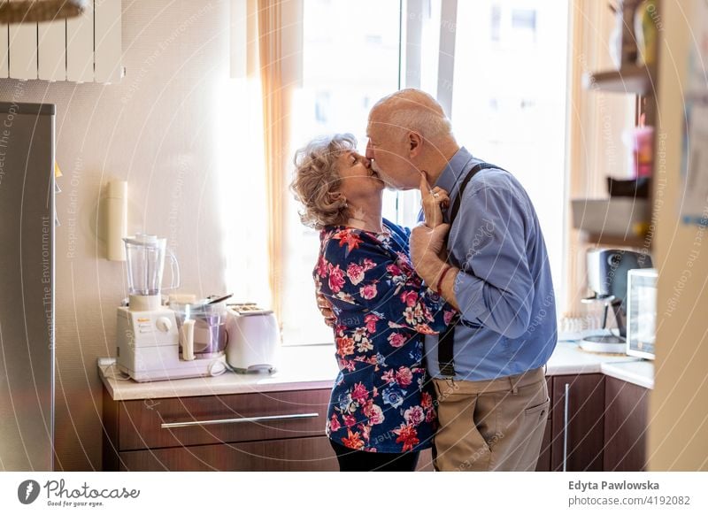 Glückliches Seniorenpaar, das sich in der Küche küsst echte Menschen offen Frau reif männlich Mann Paar Zusammensein Liebe Bonden Kaukasier älter heimwärts Haus