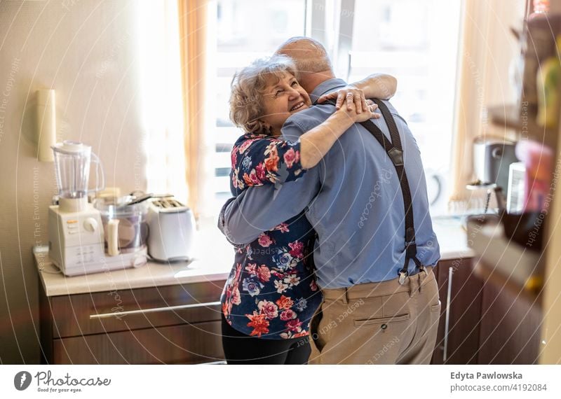 Älteres Paar umarmt und lächelnd in der Küche echte Menschen offen Frau Senior reif männlich Mann Zusammensein Liebe Bonden Kaukasier älter heimwärts Haus alt