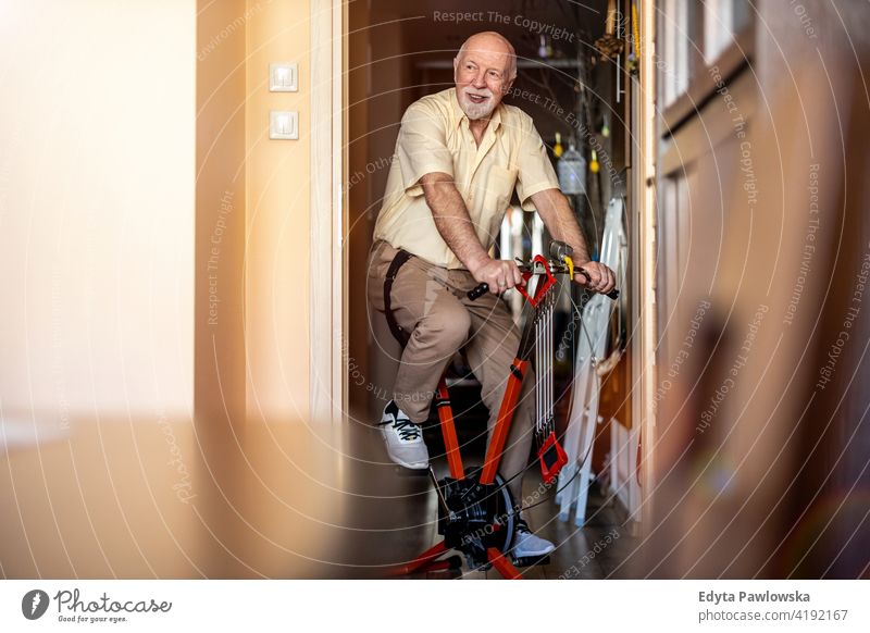 Senior Mann mit Heimtrainer zu Hause Fahrrad Zyklus stationäres Fahrrad Übung Spinnrad Fitness Sport Hobby Gesundheit aktiv ausarbeitend anstrengen Therapie