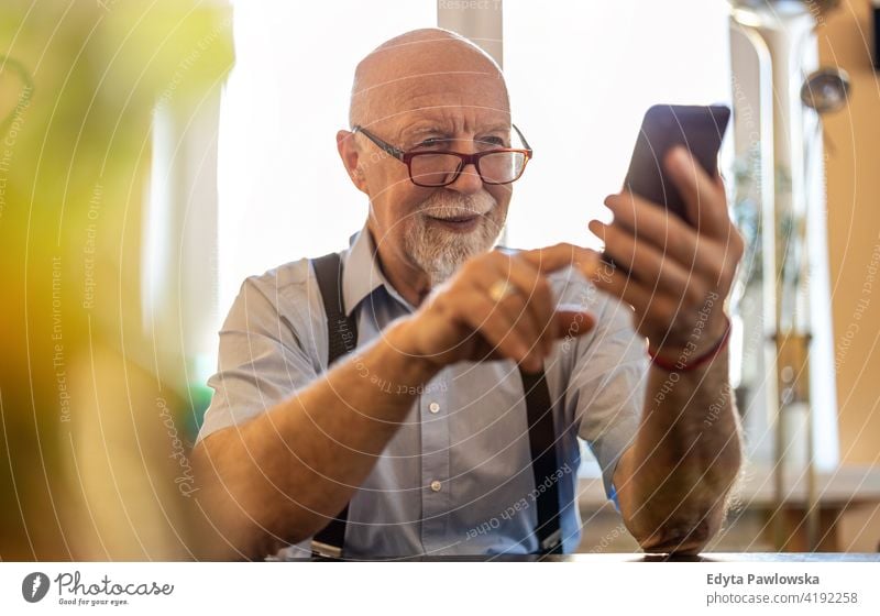 Aufnahme eines älteren Mannes, der ein Mobiltelefon zu Hause benutzt Smartphone Handy Technologie Technik & Technologie Mitteilung online modern Anschluss