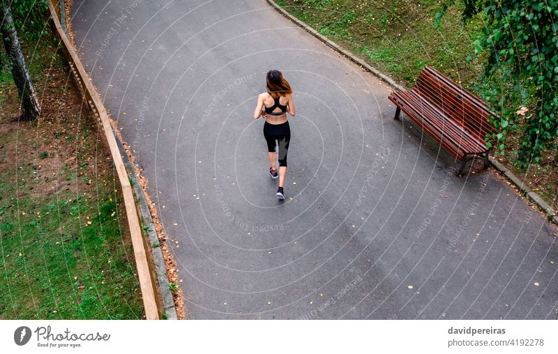 Luftaufnahme der Läuferin rückwärts Draufsicht Frau schlanke rennen Stadtpark Asphalt durchhalten Sport Overhead Athlet Fitness Gesundheit Übung jung Freizeit