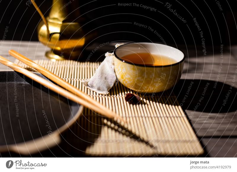 Dunkler Tee-Hintergrund mit Tasse heißem Tee auf dem Tisch. Kopierbereich für Ihr Design. Authentischer Vintage-Stil. Traditionelle Teezeremonie Anordnung