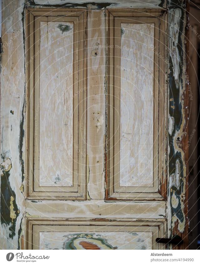 Obere Hälfte einer alten Tür in einer Altbauwohnung die viele Schichten Farbe hat, abgeschliffen wurde jedoch noch nicht neu lackiert der Türgriff ist zu sehen