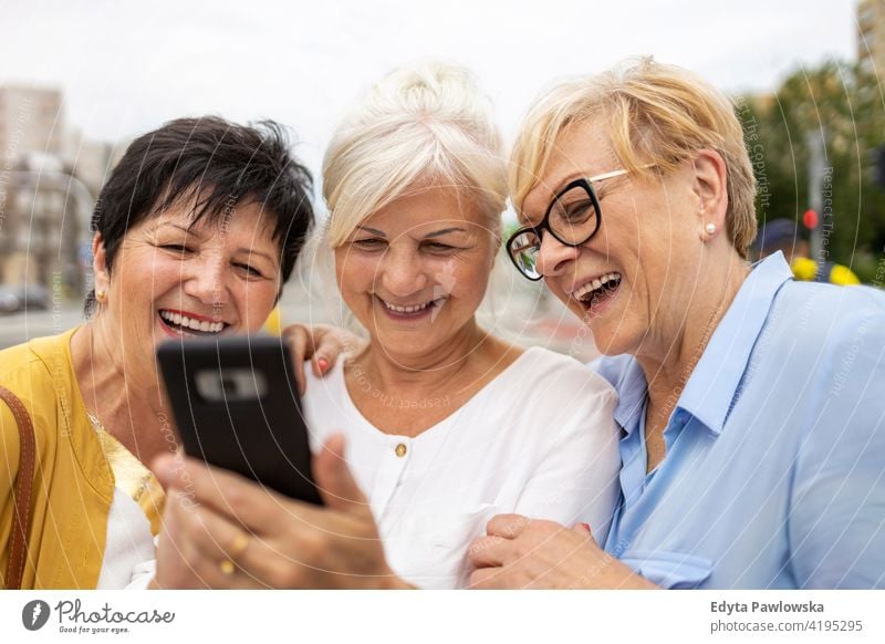 Gruppe älterer Frauen, die gemeinsam ein Smartphone benutzen Senior Menschen in den Ruhestand getreten Großmutter Freizeit Stehen selbstbewusst attraktiv urban